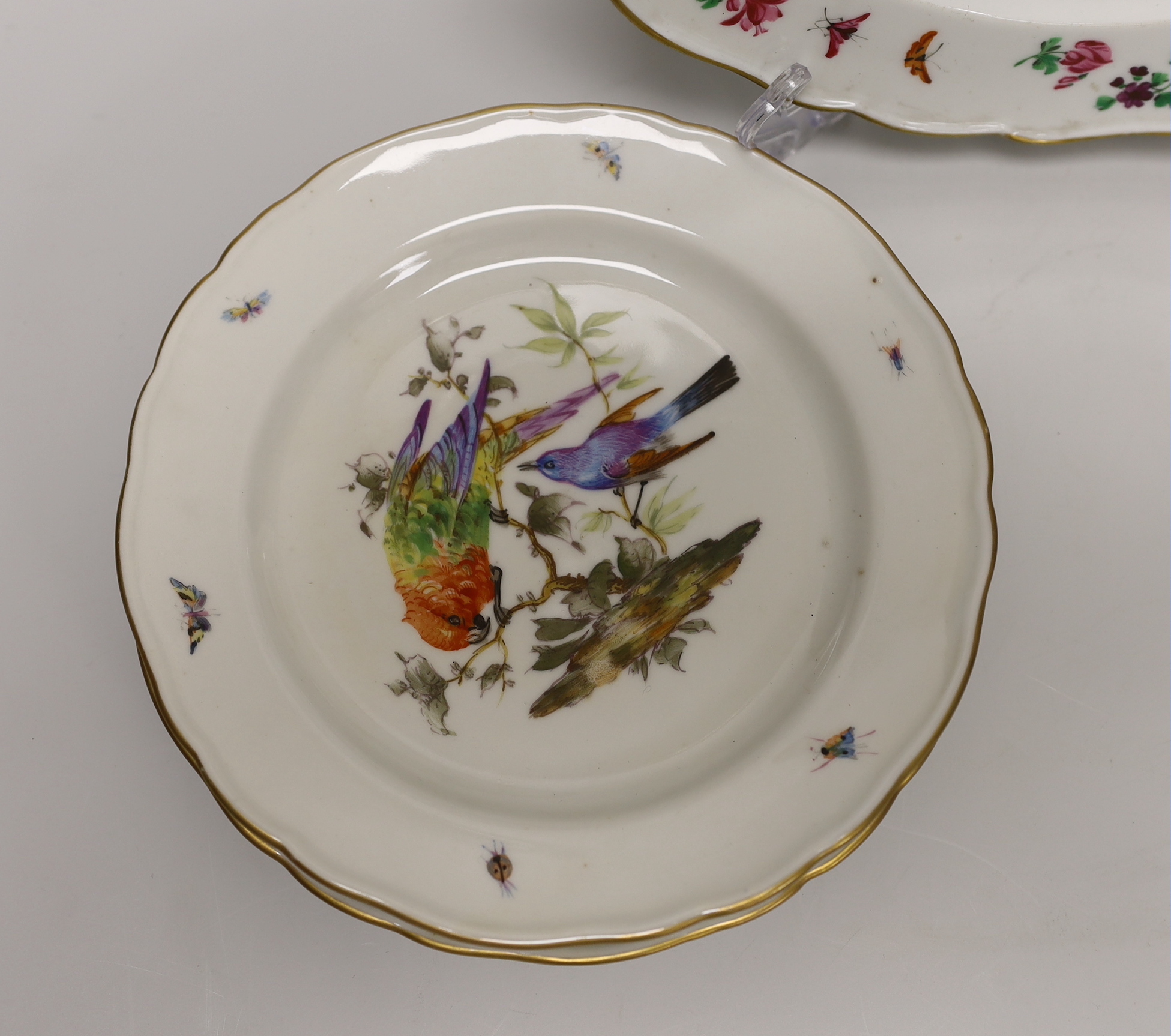 A Meissen plate with crown and fish crest boldly painted with flowers, crossed swords in blue, and four smaller plates painted with birds, probably 19th century German, 24cm in diameter